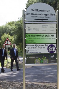 Ein Hinweisschild führt E-Bike-Fahrer mit leerem Akku direkt zur wenige Schritte entfernten Ladestation am Kronenburger See. Bild: Tameer Gunnar Eden/Eifeler Presse Agentur/epa