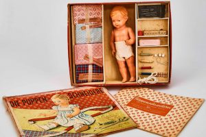 Puppen-Schneiderei: Kasten mit Puppe, Stoff und Schnittmuster zum Nähen von Puppenkleidern. Bild: Hans-Theo Gerhards/LVR