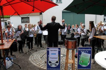 In Scheven konzertierten die Musikanten vor dem Eingang des Dorfsaales. Die aufgespannten Schirme dienten eher als Sonnenschutz. Foto: Reiner Züll