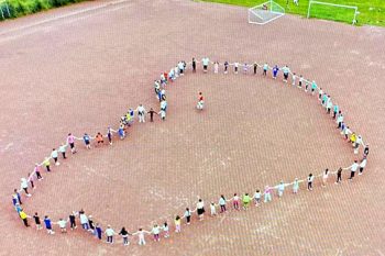 Hand in Hand für eine Herzensangelegenheit: Zum Auftakt des Spendenlaufs auf dem Kommerner Sportplatz formierten sich die Grundschulkinder zu einer Herz-Darstellung. Foto: Karwanska/OGS Kommern