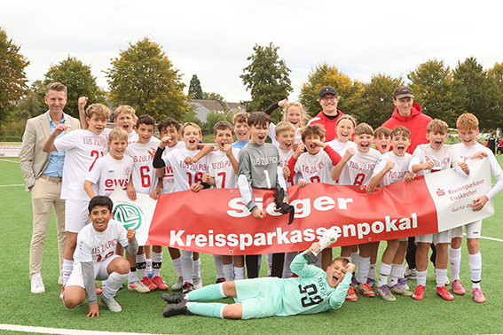 Feierlaune herrschte bei den D-Junioren vom TuS Chlodwig Zülpich, nachdem KSK-Pressesprecher Marius Linden (hinten links) den Pokal überreichte. Bild: Tameer Gunnar Eden/Eifeler Presse Agentur/epa