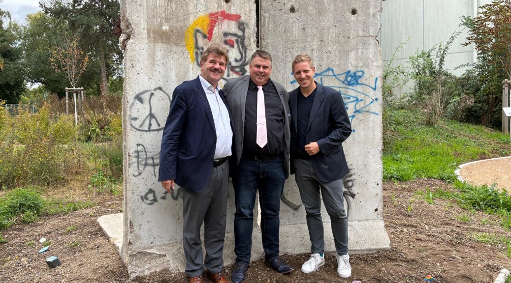 Geschichte lebendig werden lassen: KSK-Stiftungsvorstand Karl-Heinz Daniel (v. l.), Schulleiter Michael Mombaur und Landrat Markus Ramers vor den Original-Elementen der Berliner Mauer im Naturgarten der Marienschule. Foto: KSK Euskirchen