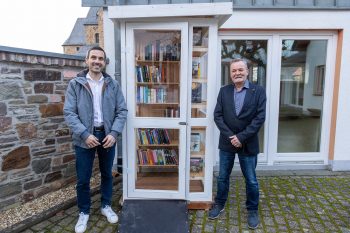 Über den neuen Bücherschrank in direkter Nähe der Nöthener Kirche freuen sich Sebastian Thur (v.l.) vom Stiftungsvorstand der Kreissparkasse Euskirchen und Ratsherr Andreas Bühl. Bild: Tameer Gunnar Eden/Eifeler Presse Agentur/epa